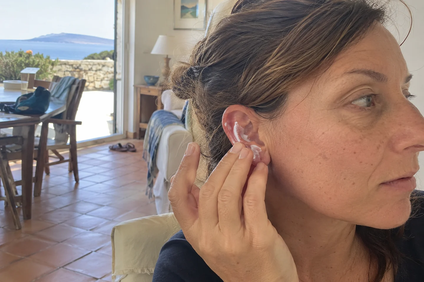 Une femme applique de la crème solaire sur une oreille