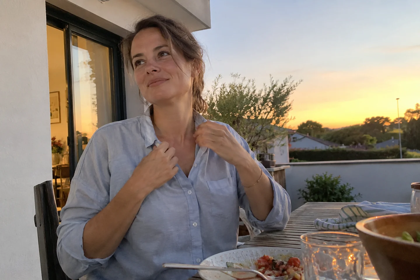 Une femme ajuste le col de sa chemise en terrasse