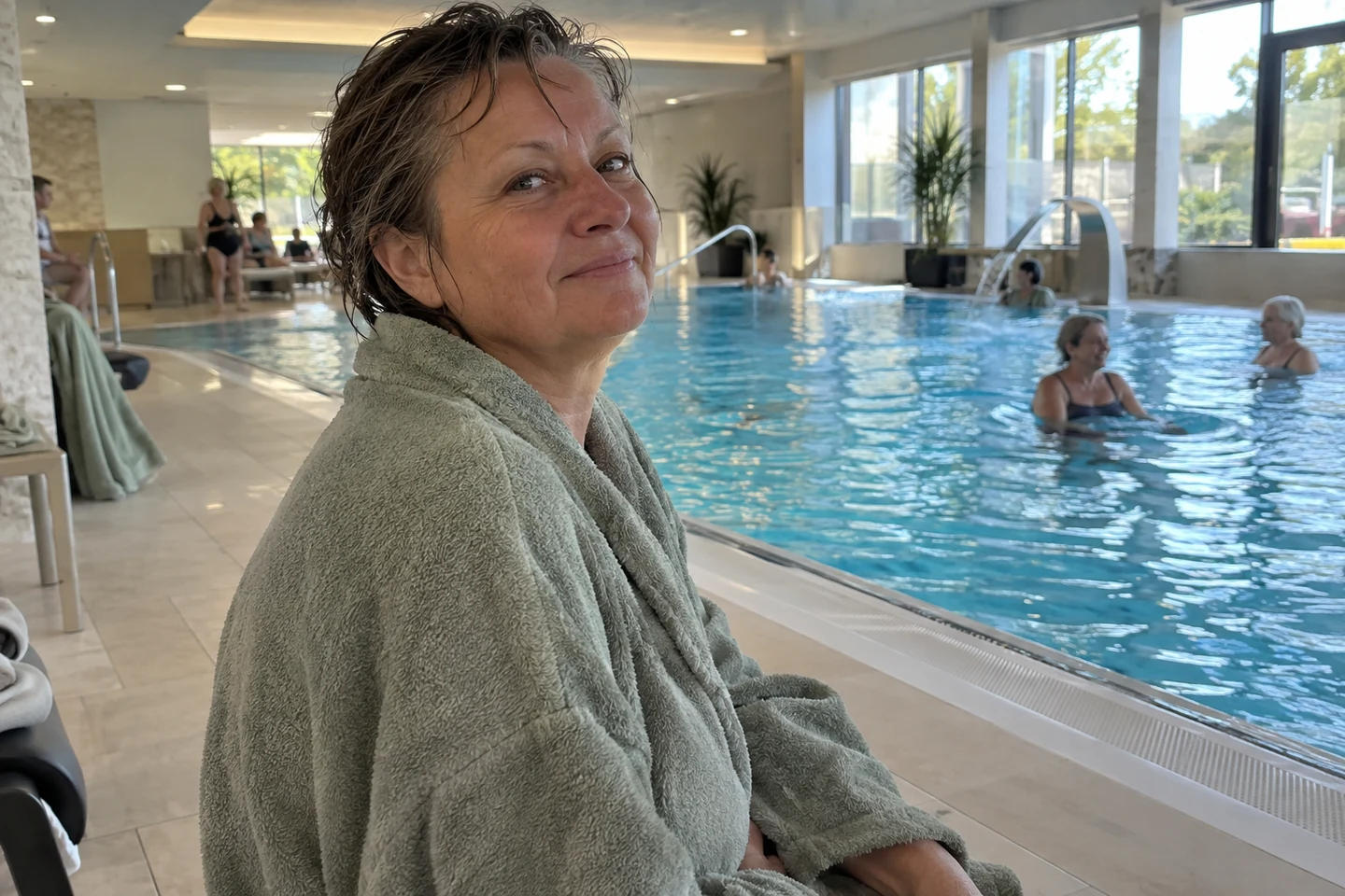 Femme en peignoir au bord d’une piscine intérieure après la baignade